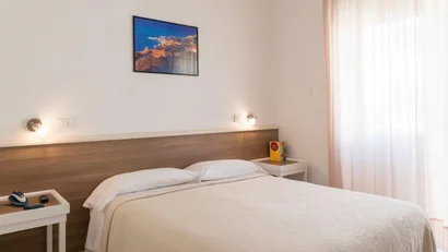 Camera da letto semplice con letto matrimoniale e finestre con tende leggere