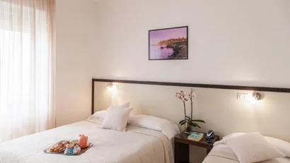 Camera con due letti singoli, lenzuola bianche e colazione su un vassoio