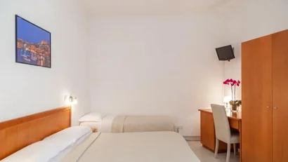 Camera d'albergo semplice con due letti, scrivania, sedia e armadio