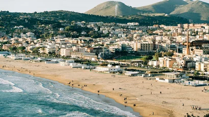 Spiaggia con persone e città ai piedi di montagne verdi