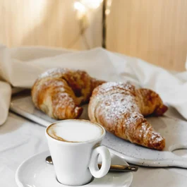 Tazza di cappuccino con due croissant su un tavolo bianco