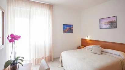 Camera da letto luminosa con letto matrimoniale, scrivania e orchidea