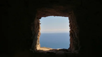 Vista del mare attraverso una finestra rustica in una parete di pietra